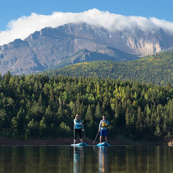 promo_visitor_3_sq two stand-up paddleboarders on a smooth lake, with the mountains in the background