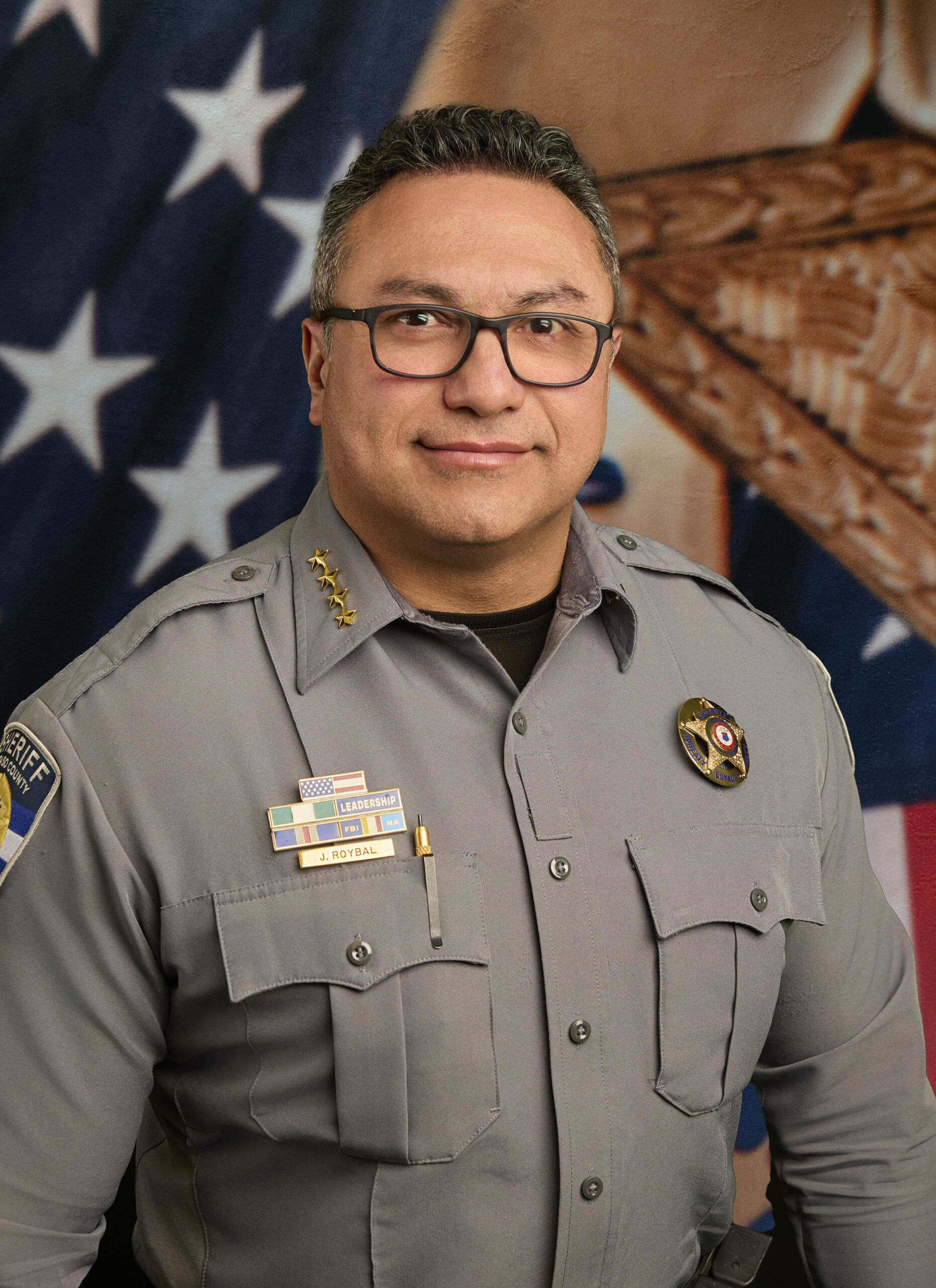 Sheriff Roybal posing in front of the American flag